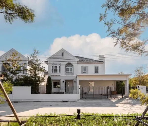 Detached House for rent or sale in Bang Phli, Samut Prakan - Front view of a two-storey white detached house with gated carport and landscaped yard under a blue sky in Bang Phli.