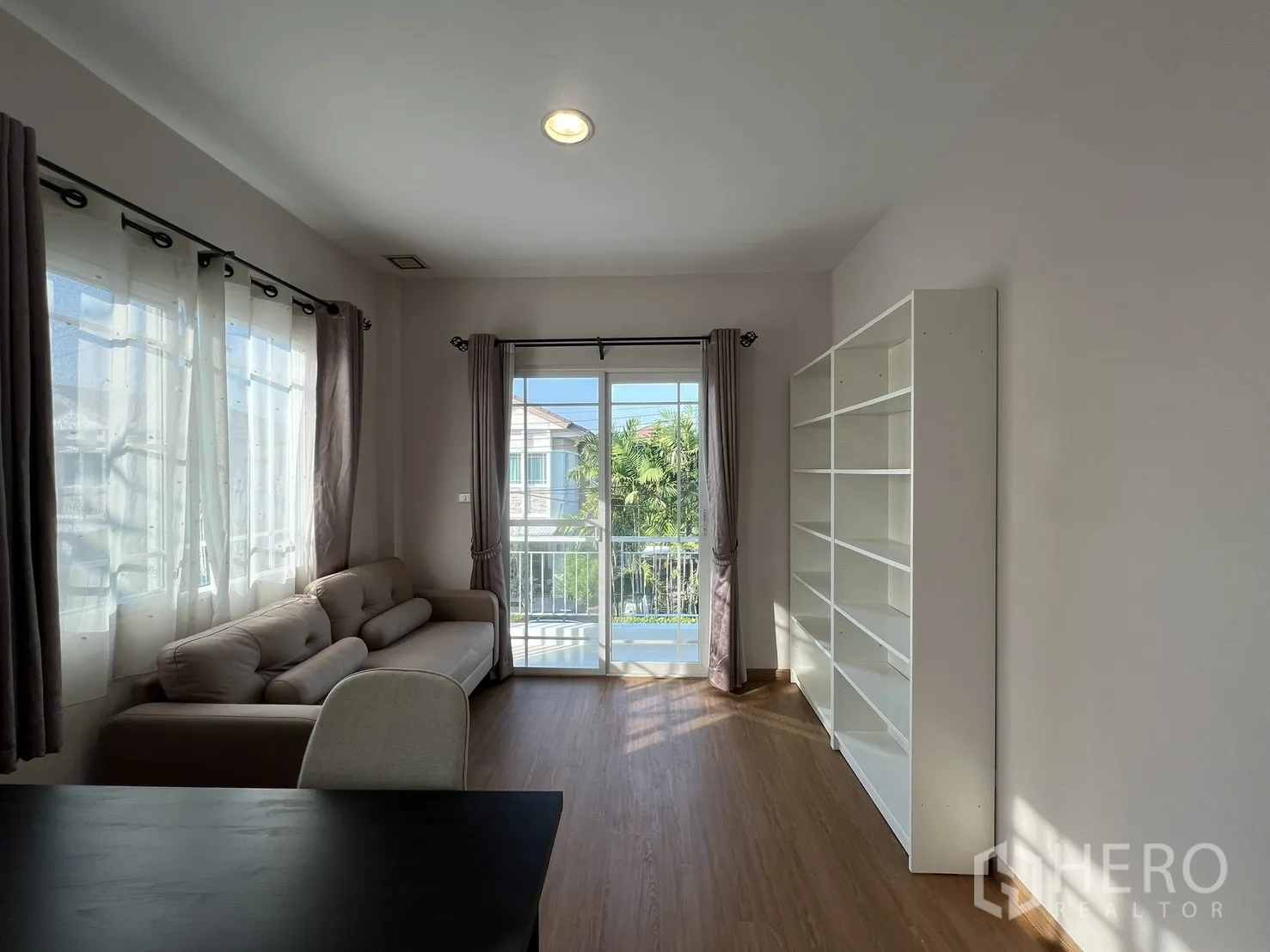 บ้านเดี่ยว for rent in Bang Kapi, Bangkok - ห้องนั่งเล่นชั้นบนมีชั้นวางของและทางออกสู่ระเบียงมองเห็นเพื่อนบ้าน.