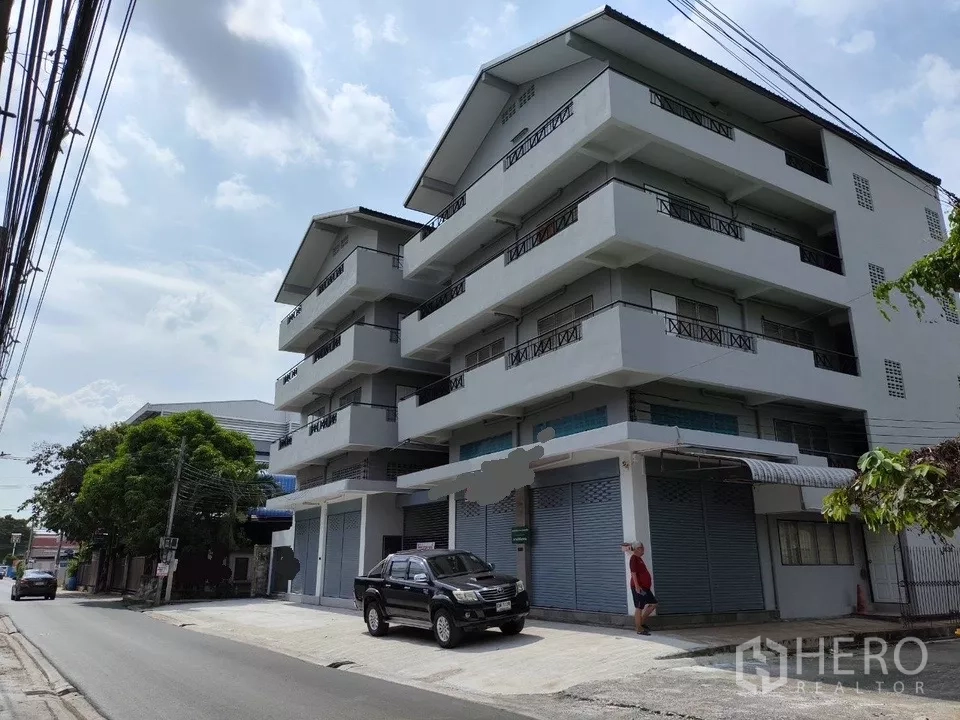 Shophouse for rent in Bueng Kum, Bangkok - Multi-storey shophouse block with balconies and closed roller shutters on a quiet street.