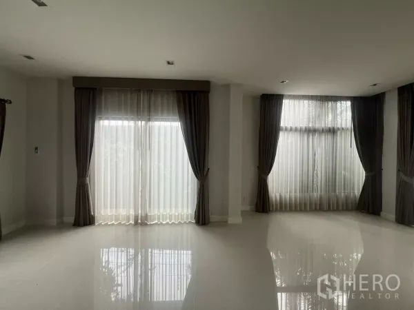 Detached House for sale in Bang Kapi, Bangkok - Spacious living room with large windows and sheer drapes bringing in natural light.