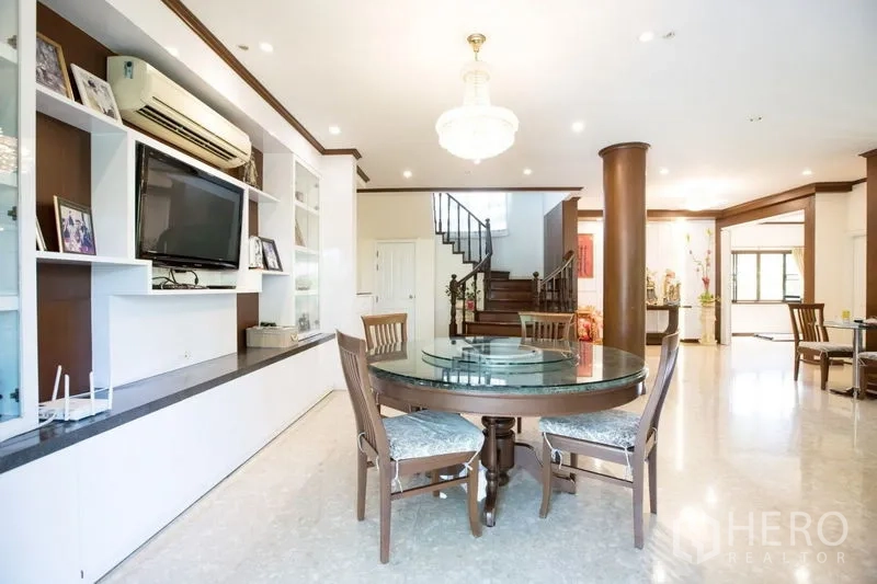 บ้าน ขายในLat Krabang, Bangkok - พื้นที่ทานข้าวโต๊ะกลม โคมแชนเดอเลียร์ ชั้นวางบิวท์อิน และบันไดเป็นฉากหลัง