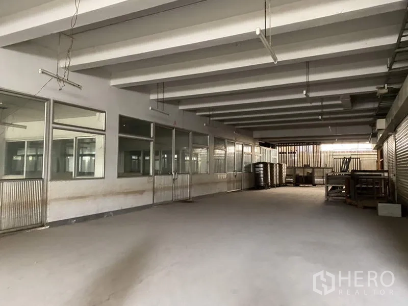 Factory for sale in Khlong Luang, Pathum Thani - Covered storage area with windows and roller doors inside the warehouse.