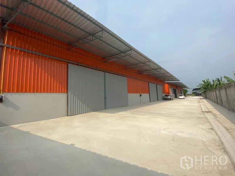 คลังสินค้า ให้เช่าในBang Yai, Nonthaburi - ด้านหน้าโกดังสีส้ม ประตูบานเลื่อนสีเทา ทางรถบรรทุกเข้าออกสะดวก