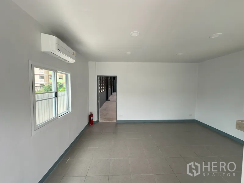 Factory for rent in Khlong Luang, Pathum Thani - Clean tiled office space with air‑conditioning and rear access doorway.