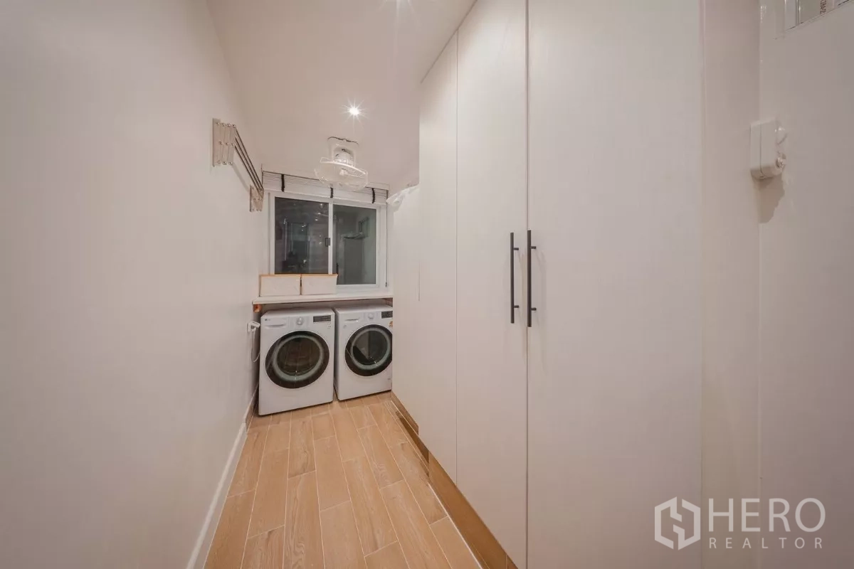 Condominium for rent in Yan Nawa, Bangkok - Laundry room with front-load washer and dryer, tall white cabinets and a window.