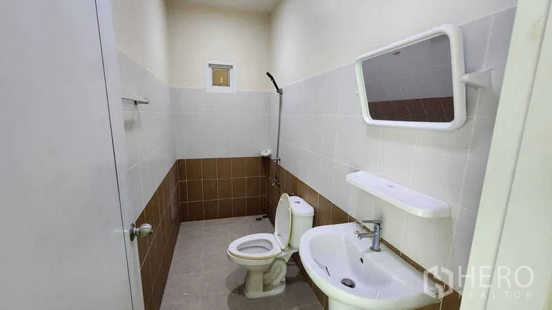 Factory for rent in Samut Sakhon - Clean restroom with toilet, sink, mirror and tiled walls.