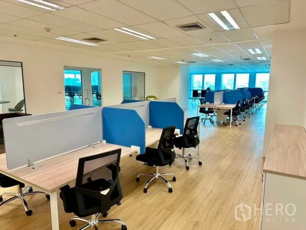 办公空间 出租 - 开放式办公室，成排工位配蓝色隔板、木纹地板与明亮窗景，位于曼谷Huai Khwang。