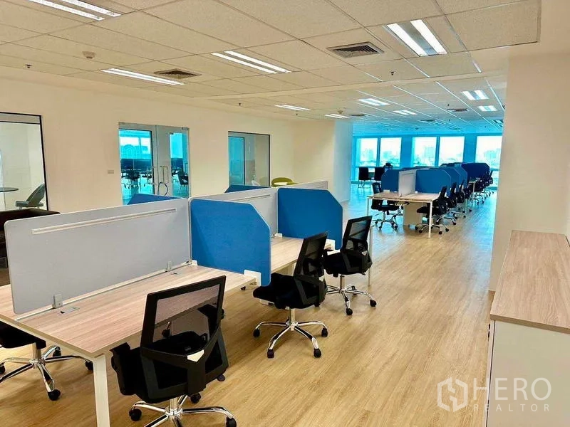 办公空间 出租 - 开放式办公室，成排工位配蓝色隔板、木纹地板与明亮窗景，位于曼谷Huai Khwang。