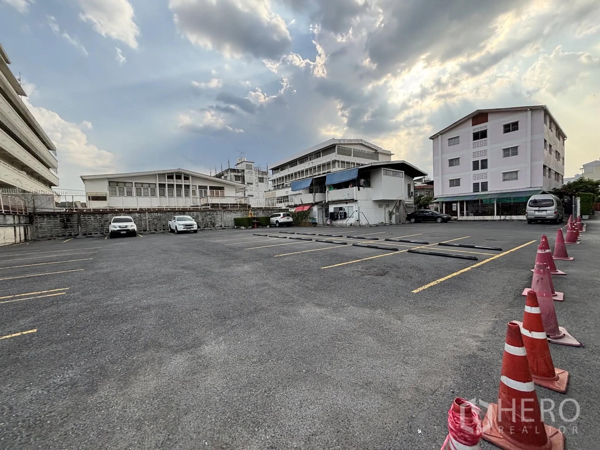 Land for rent in Sathon, Bangkok - Wide view of the open car park with cones, bay markers, and nearby residential blocks.