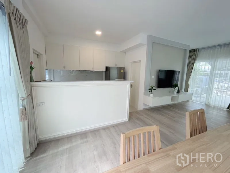 联排别墅 出租在Prawet, Bangkok - 开放厨房与餐区相连，设早餐吧台并可见电视墙。