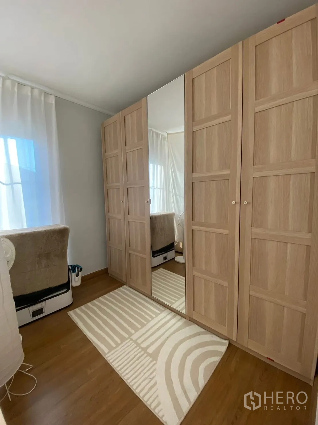 Semi-detached House for rent in Bang Phli, Samut Prakan - Bright dressing room with a wall of light wood wardrobes and a mirrored door.