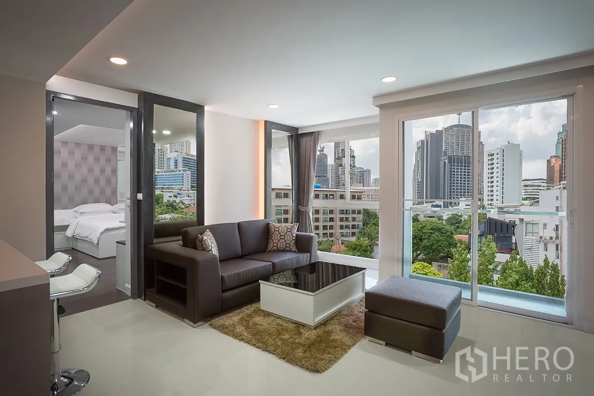 คอนโด for rent in Khlong Toei, Bangkok - ห้องนั่งเล่นมีหน้าต่างสูงจรดเพดาน มองเห็นวิวสกายไลน์ของเมือง ข้างๆ ห้องนอน