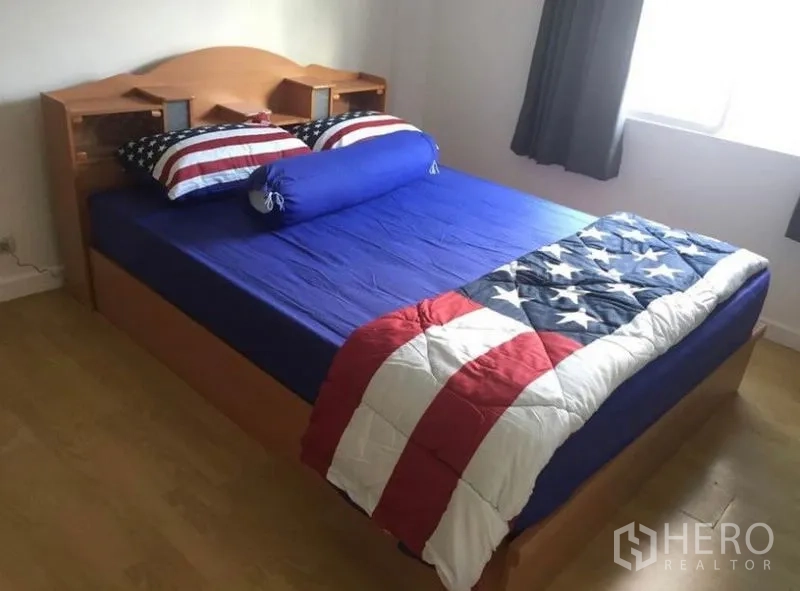 联排别墅 出租在Prawet, Bangkok - 明亮卧室，木质床架，蓝色床品，木地板与窗边采光。