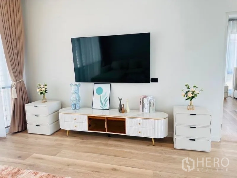 บ้าน ให้เช่าหรือขายในBang Kapi, Bangkok - ผนังทีวีติดตั้งจอพร้อมตู้วางทีวีสีขาว พื้นไม้โทนอ่อน.