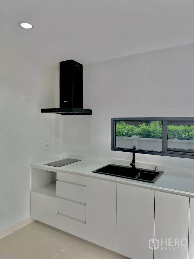 บ้าน ให้เช่าหรือขายในPrawet, Bangkok - ครัวสไตล์โมเดิร์นสีขาว เตาไฟฟ้า อ่างล้างจานสีดำ และเครื่องดูดควัน