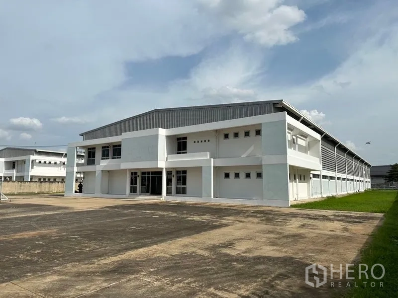 工厂 出租在Phra Nakhon Si Ayutthaya - 工厂转角外观，草坪边带与长条通风金属侧墙。