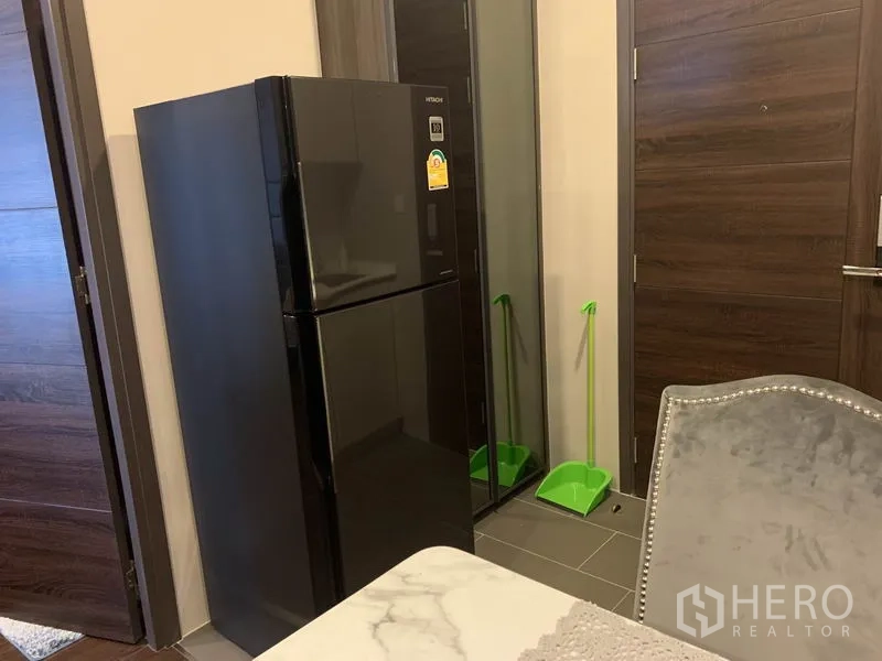 公寓 出售在Watthana, Bangkok - 入户角落配黑色双门冰箱与木质房门，布局紧凑。