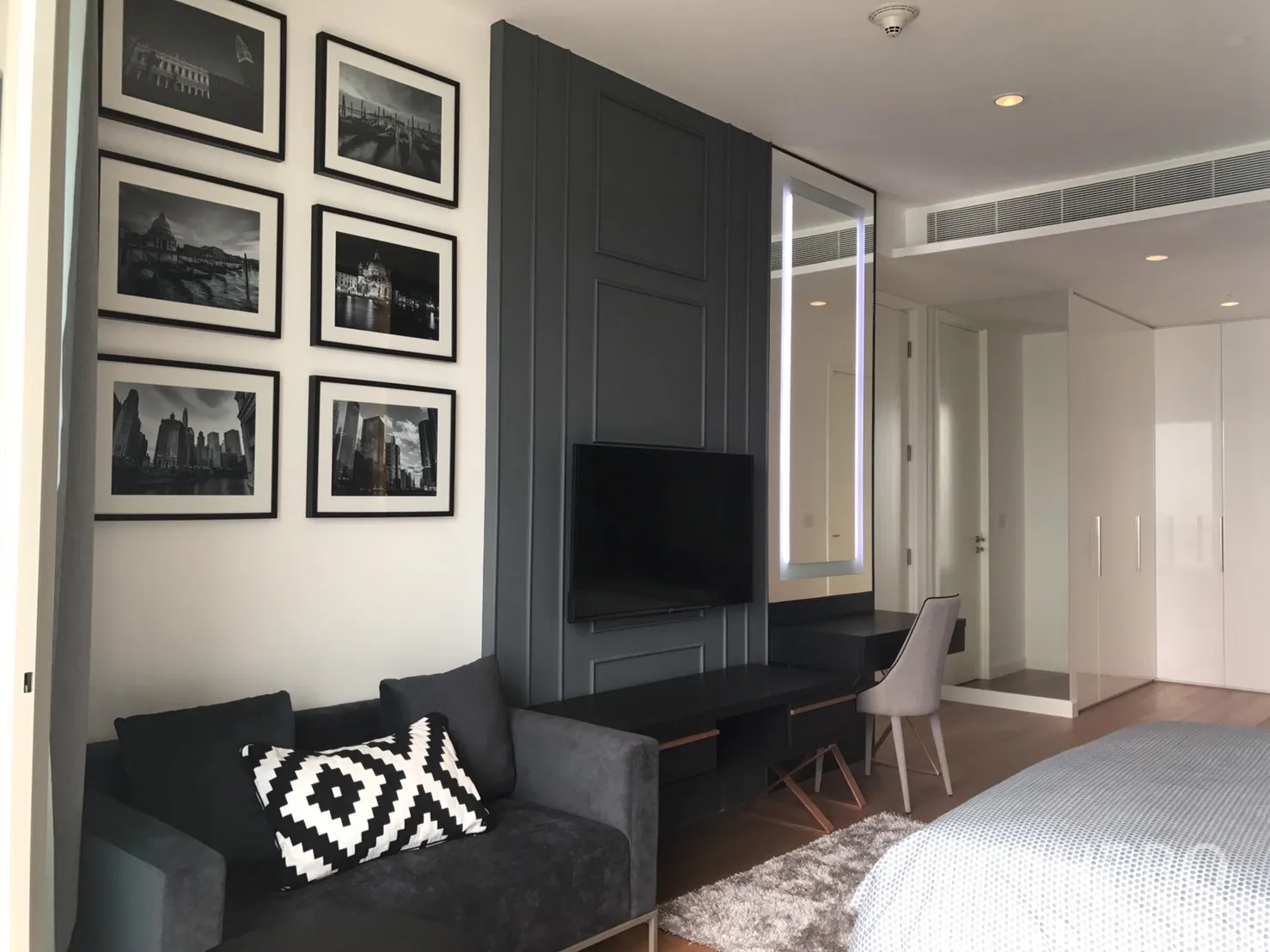 คอนโด ให้เช่าในPathum Wan, Bangkok - มุมห้องนอนมีกรอบรูป ทีวีติดผนัง และโซฟาขนาดกะทัดรัด