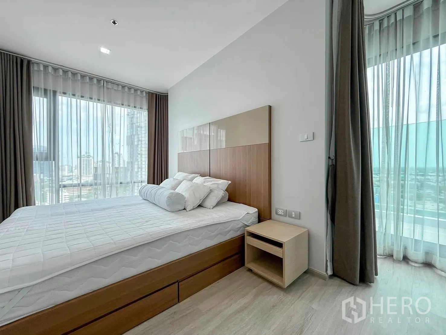 Condominium for rent in Khlong Toei, Bangkok - Corner bedroom with wraparound windows and city views by the terrace glass.