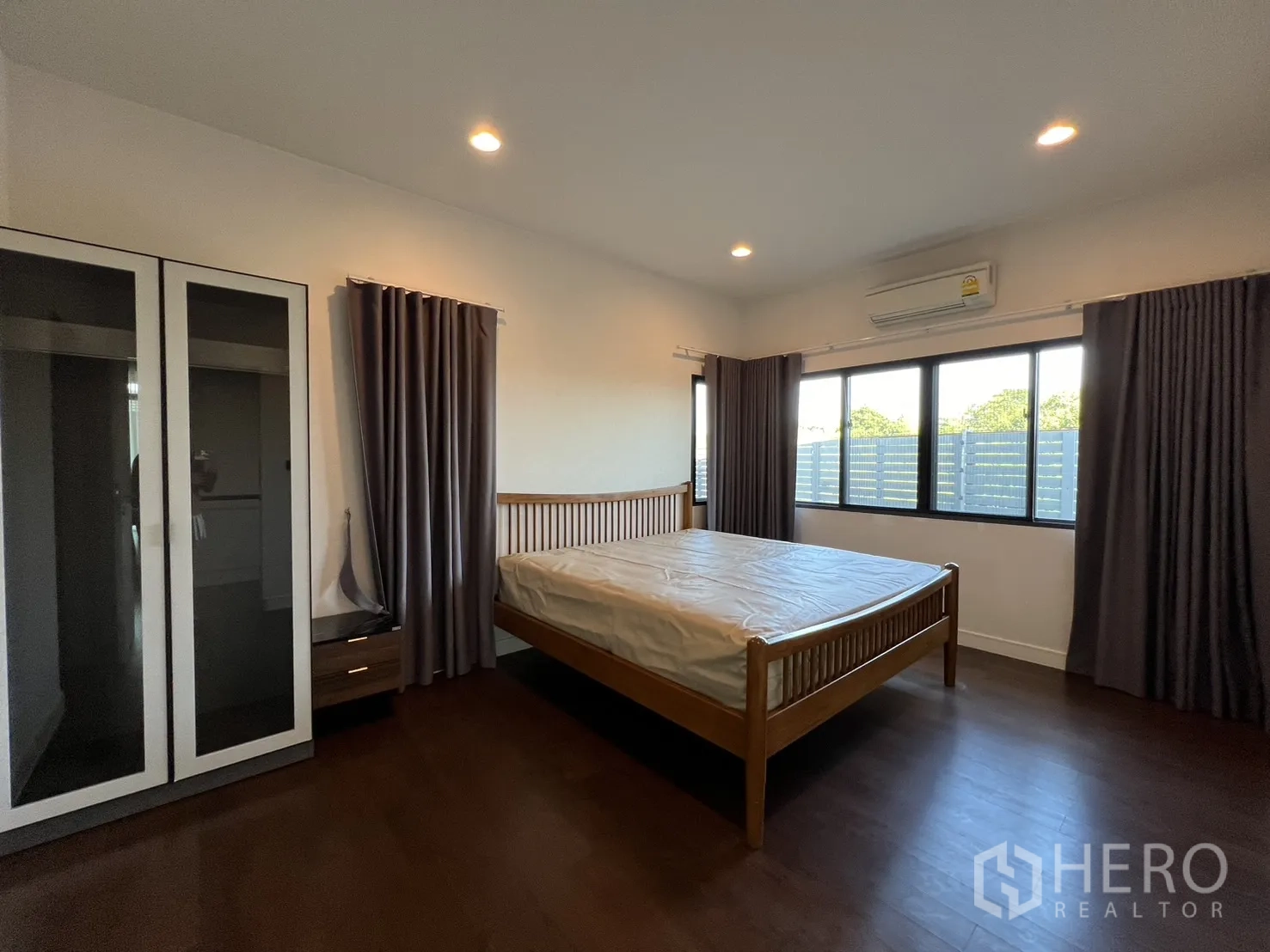 Detached House for rent or sale in Bang Kapi, Bangkok - Bright bedroom with large windows, curtains and freestanding wardrobe.
