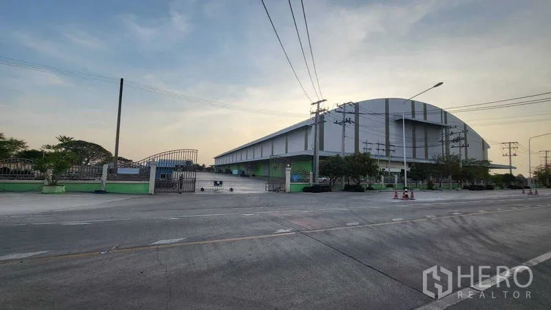 工厂 出租在Sai Noi, Nonthaburi - 工厂外部转角视图，围栏入口与临街电力线一并可见。