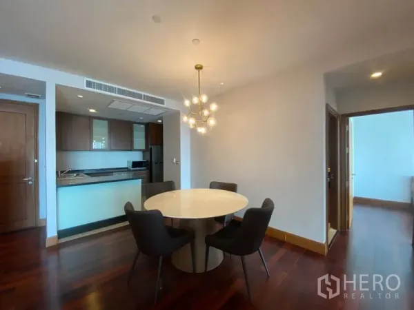 公寓 出租在Sathon, Bangkok - 开放式餐厨空间，吊灯点缀与深色木地板。