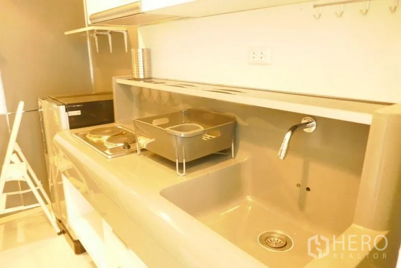 คอนโด ให้เช่าหรือขายในKhlong San, Bangkok - ครัวขนาดกะทัดรัด มีซิงก์ เตาไฟฟ้า ตู้เย็น และฉากหลังมันวาว