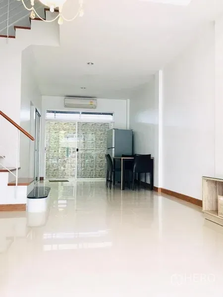 联排别墅 出租在Prawet, Bangkok - 采光充足的客餐厅一体空间，亮面地砖与推拉玻璃门和空调。