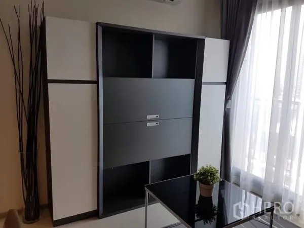 公寓 出租在Khlong Toei, Bangkok - 黑白色收纳柜，旁为带纱帘的玻璃门通向阳台。