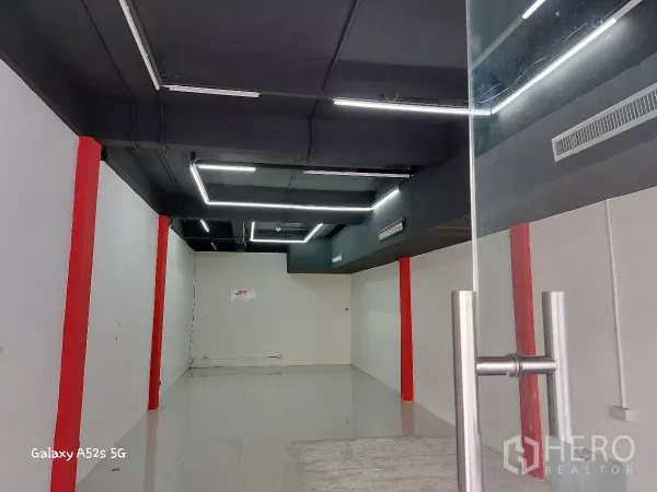 พื้นที่ขายปลีก ให้เช่าในKhlong Toei, Bangkok - มุมมองจากทางเข้า แสดงไฟดีไซน์สมัยใหม่ เพดานเปิดท่อสีดำและผนังขาวสะอาด