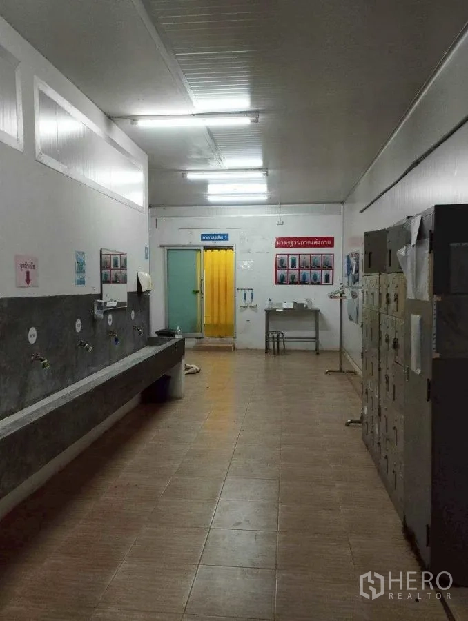 Factory for rent or sale in Mueang Nakhon Pathom, Nakhon Pathom - Hygiene and locker room with multiple sinks, lockers, and safety signage.