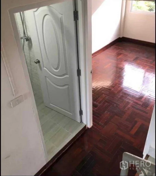 Home Office for rent or sale in Watthana, Bangkok - Bedroom with glossy parquet floor and adjoining bathroom with shower and a window.