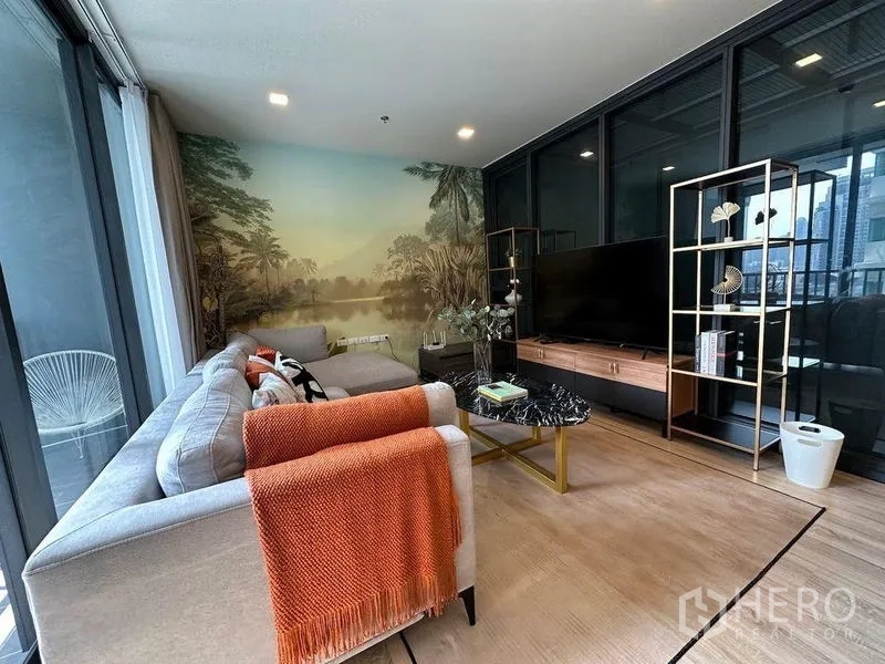 公寓 出租在Ratchathewi, Bangkok - 客厅设转角沙发对电视墙，风景壁画与玻璃隔断。