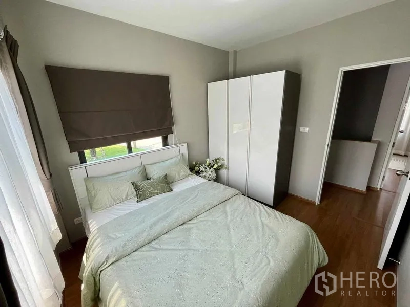 Townhouse for sale in Sai Mai, Bangkok - Second bedroom with bed, wardrobe, and garden-facing windows.