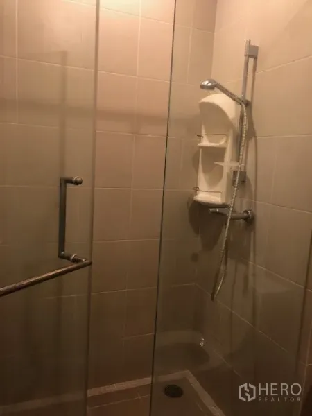 公寓 出租在Khlong San, Bangkok - 浴室为玻璃淋浴间与手持花洒，米色墙砖。