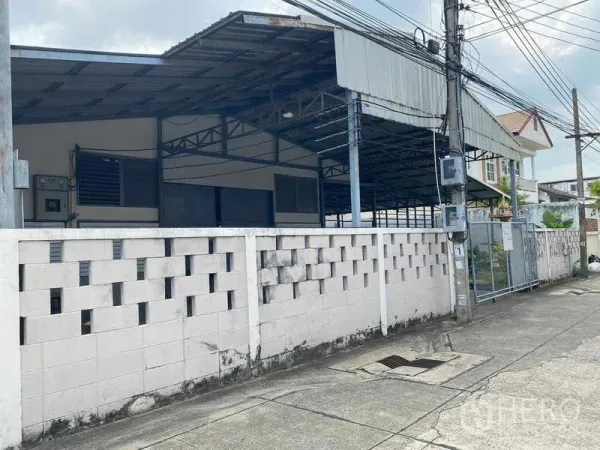 Warehouse for rent in Bang Sue, Bangkok - Street view of gated warehouse with perimeter wall and roofed structure in Bang Sue.