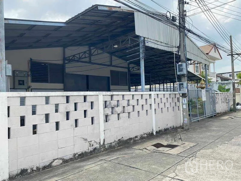 Warehouse for rent in Bang Sue, Bangkok - Street view of gated warehouse with perimeter wall and roofed structure in Bang Sue.
