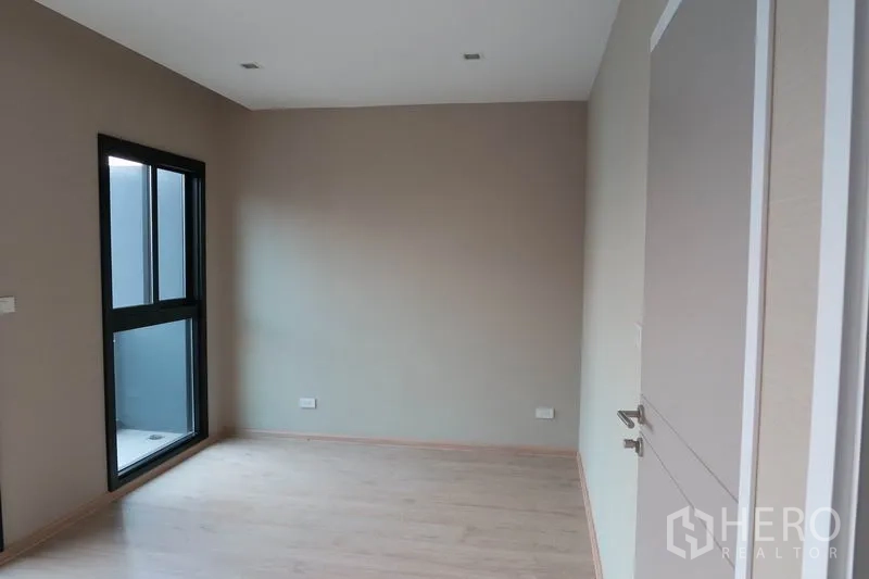 ทาวน์เฮาส์ ให้เช่าในSuan Luang, Bangkok - ห้องนอนมีหน้าต่างและประตูออกระเบียงเล็ก พื้นไม้สีอ่อน