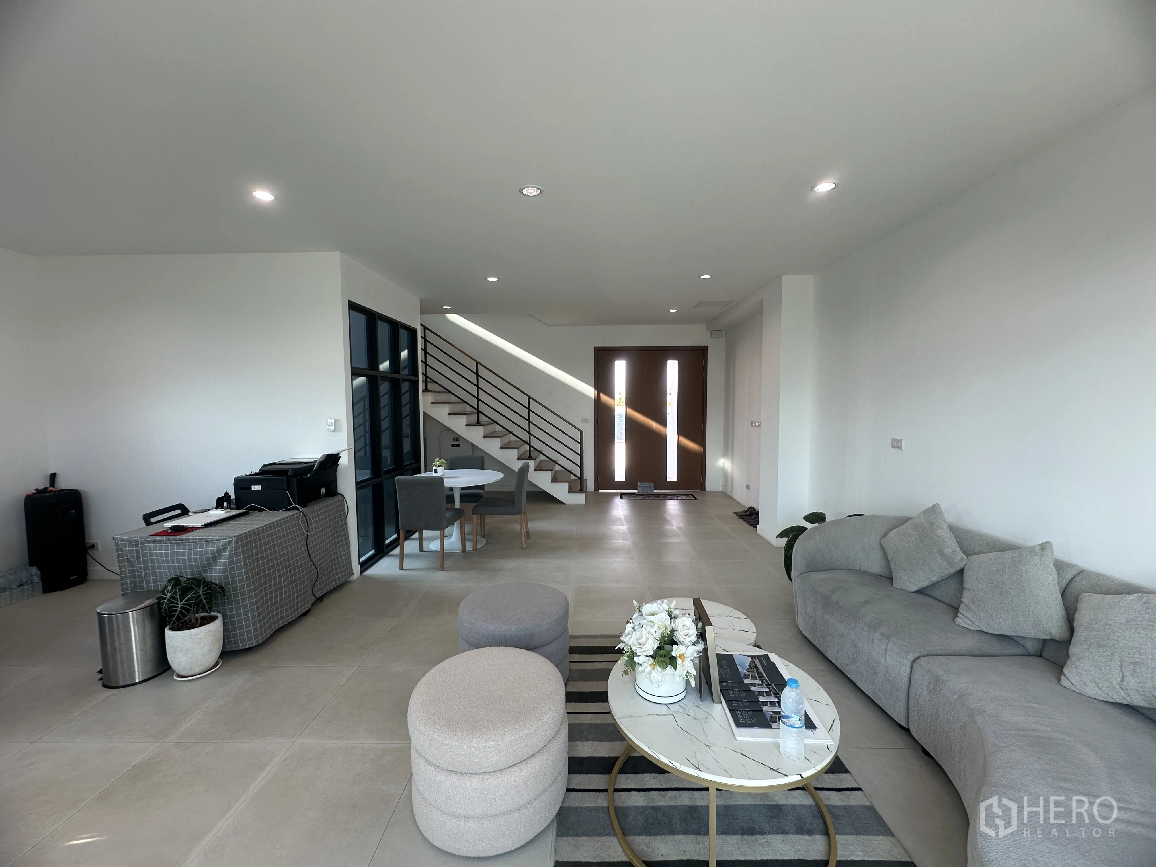 Home Office for sale in Khlong Luang, Pathum Thani - Living area facing the entry with staircase, sofas, coffee table, and wide floor tiles.