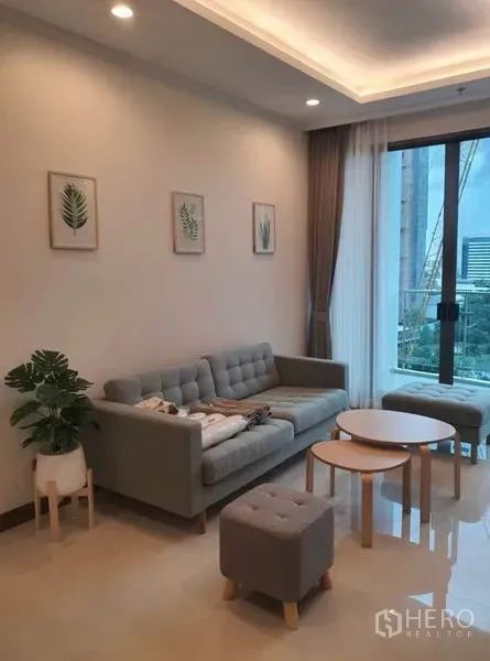 คอนโด ให้เช่าในWatthana, Bangkok - พื้นที่นั่งเล่นอบอุ่นด้วยโซฟาสีเทา สตูล และโต๊ะกลางข้างประตูระเบียงกับผ้าม่านโปร่ง