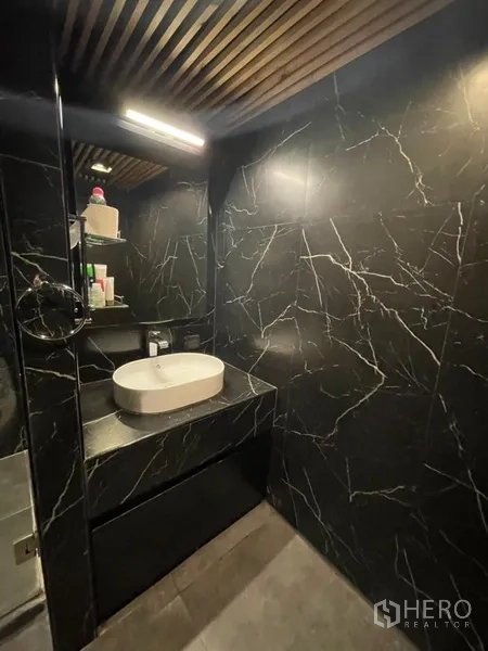 Condominium for sale in Chatuchak, Bangkok - Contemporary bathroom with black marble tiles, vessel sink and warm lighting.