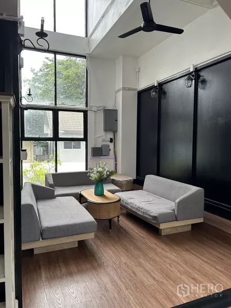 带办公室的家 出租或出售在Phra Khanong, Bangkok - 挑高双层客区，落地窗、吊扇，可见绿意景观。