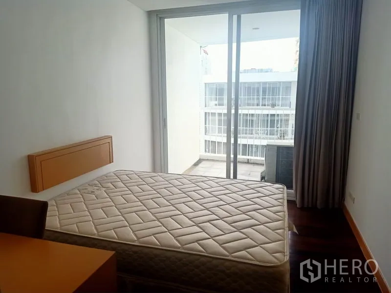 Condominium for rent in Watthana, Bangkok - Bedroom opening to a balcony through sliding glass doors with a courtyard view.