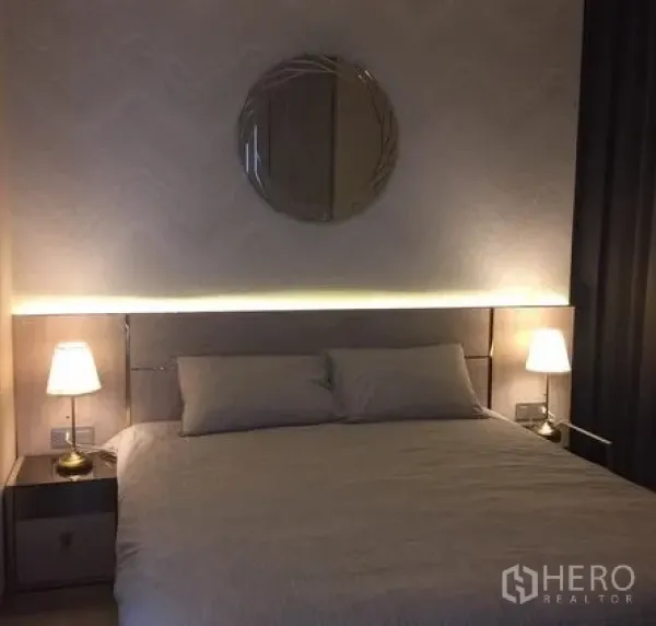 Condominium for rent in Watthana, Bangkok - Bedroom with warm ambient lighting, twin bedside lamps and upholstered headboard.