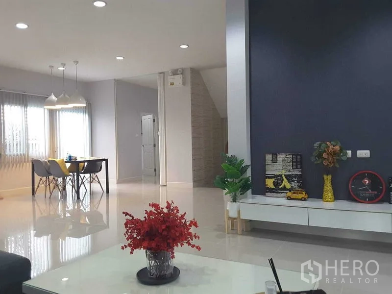 บ้าน ให้เช่าในLam Luk Ka, Pathum Thani - โถงนั่งเล่น–รับประทานอาหารแบบเปิดโล่ง แสงสว่างดี มีโคมไฟแขวนและผนังจุดเด่นสีเข้ม