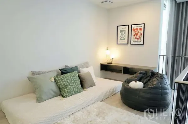 Detached House for rent in Saphan Sung, Bangkok - Cozy family lounge with low daybed, beanbag chair and warm lighting beside a railing.