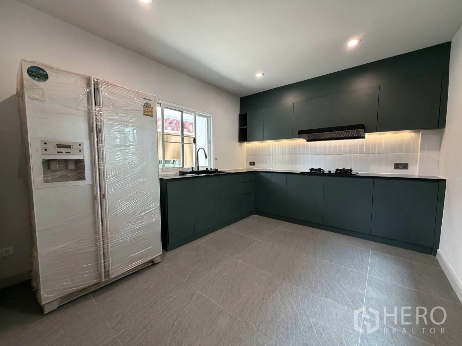 Detached House for rent in Suan Luang, Bangkok - Contemporary L-shaped kitchen with built-in cabinets and side-by-side fridge.