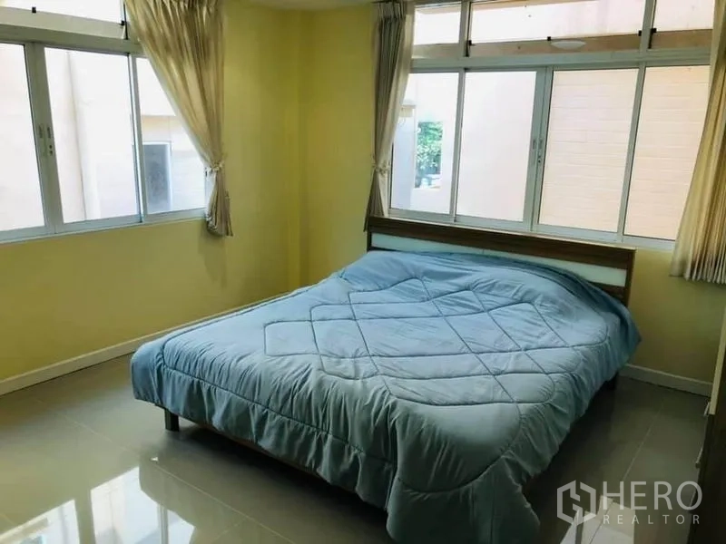 Detached House for rent in Watthana, Bangkok - Bright bedroom with multiple windows and a double bed with a blue duvet.