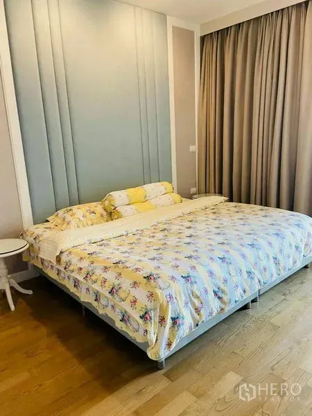 Condominium for rent in Watthana, Bangkok - Bright bedroom with a king bed, feature headboard wall, wood flooring, and full curtains.