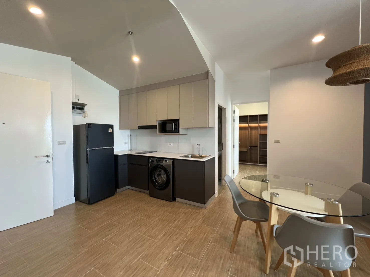 Condominium for rent in Bang Kapi, Bangkok - Kitchen and dining beneath a rattan pendant next to a blue accent wall.